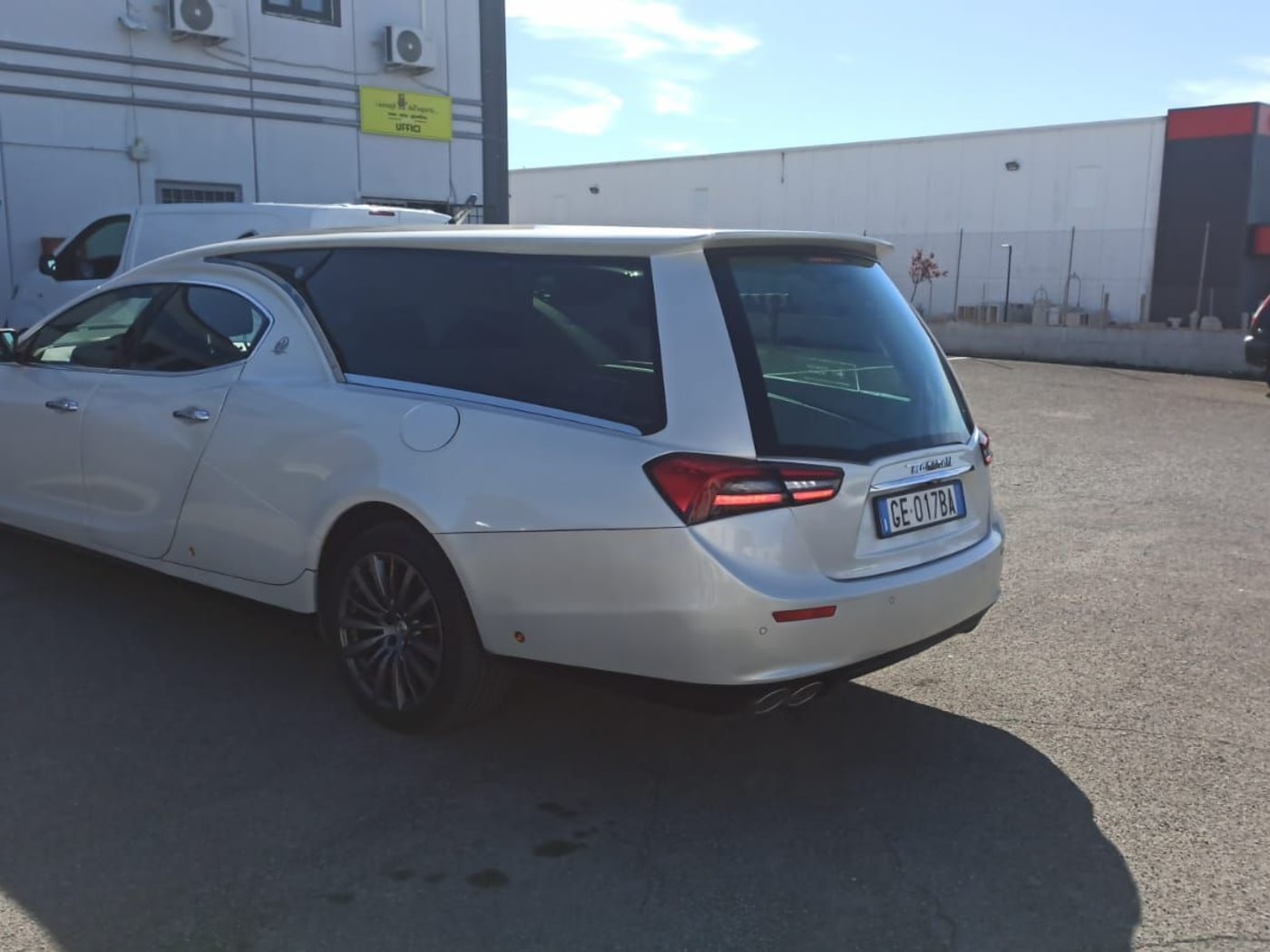 Un carro funebre bianco parcheggiato accanto alla rimessa