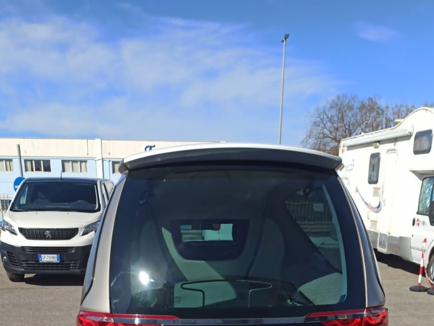 Il retro di un carro funebre bianco, con il portellone chiuso