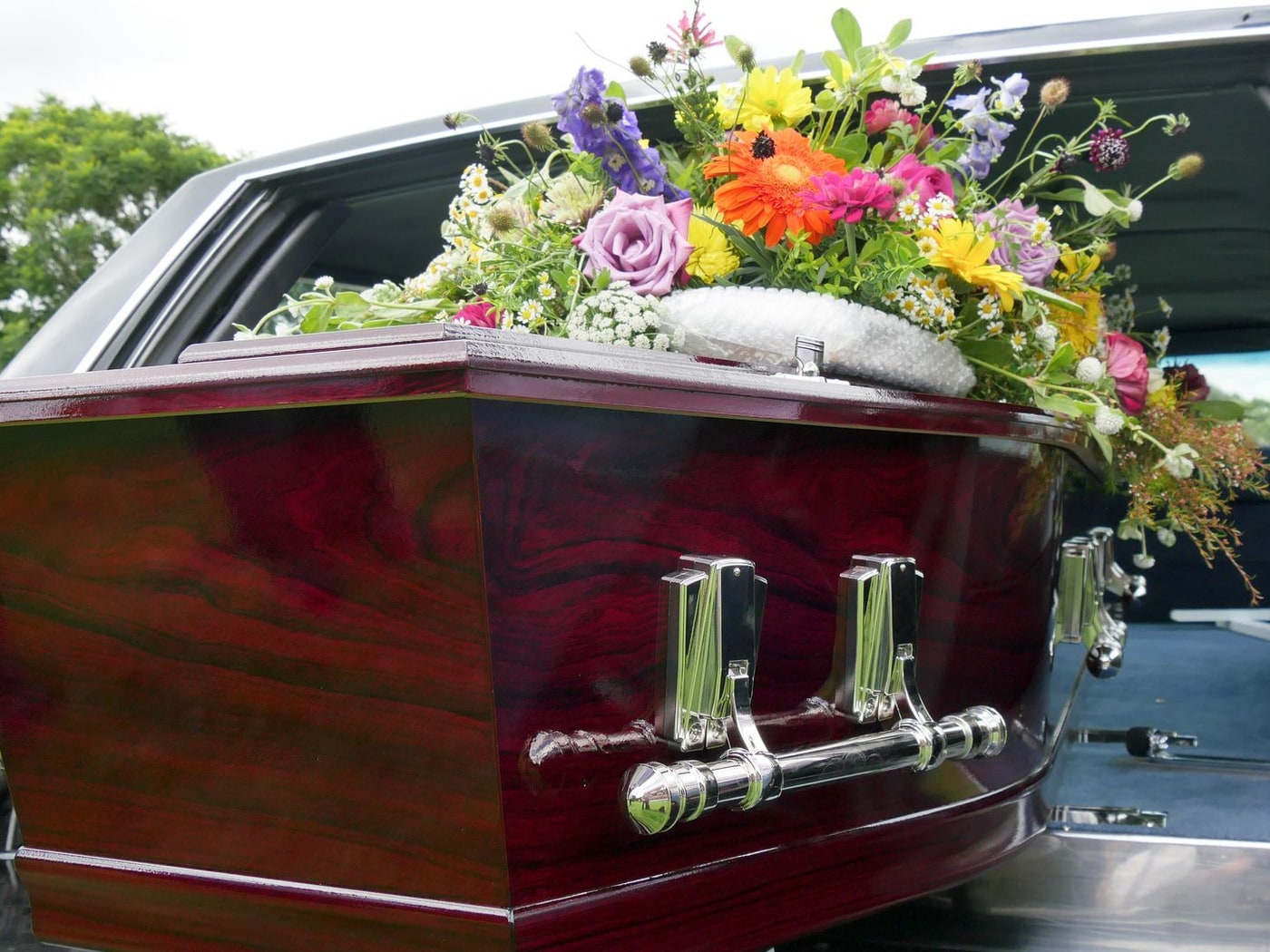 Un cofano coperto di fiori caricato sul carro funebre